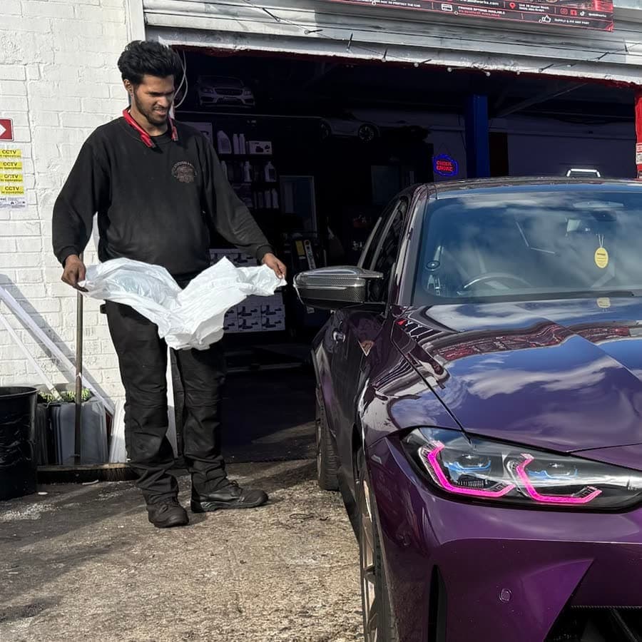 Technician with a purple BMW M3 outside the Abidworks workshop, Grays
