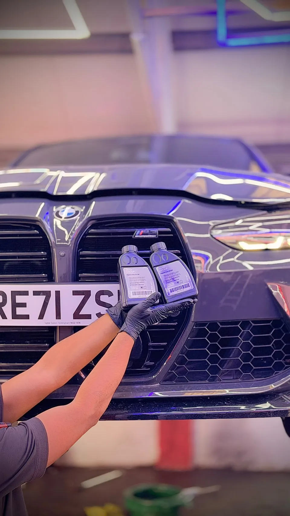 Oil for a grey BMW M3 held up in front of its grille