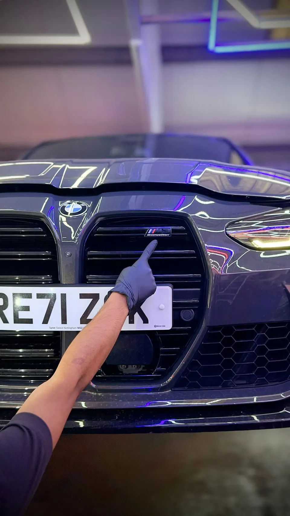 The M badge on the grille of a grey BMW M3