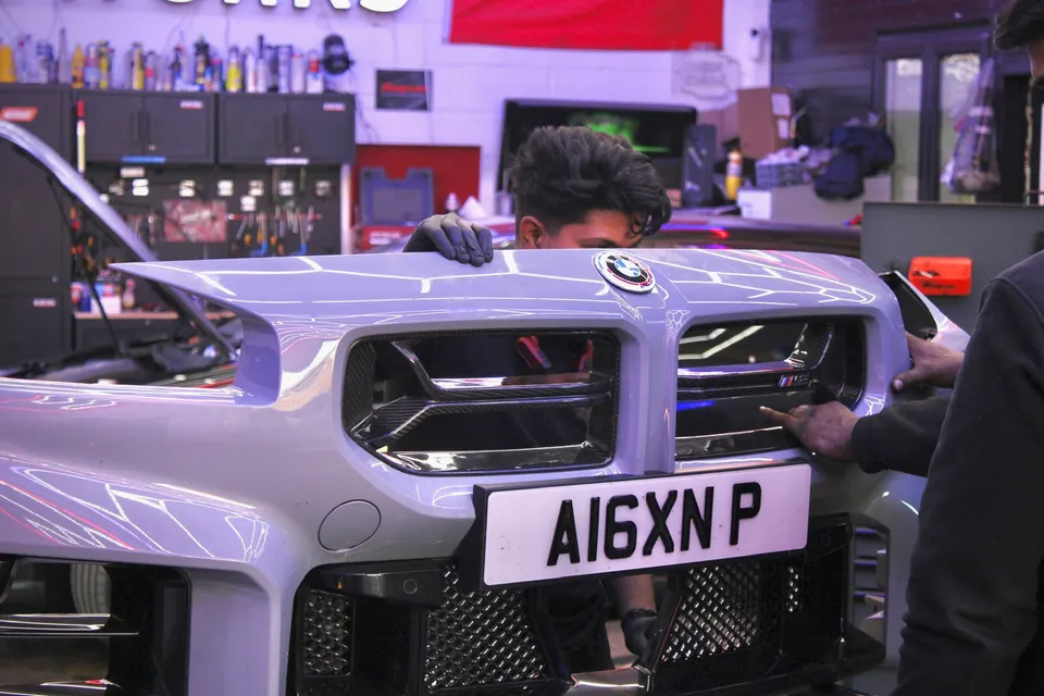 Technicians fitting the front grille of a BMW M2