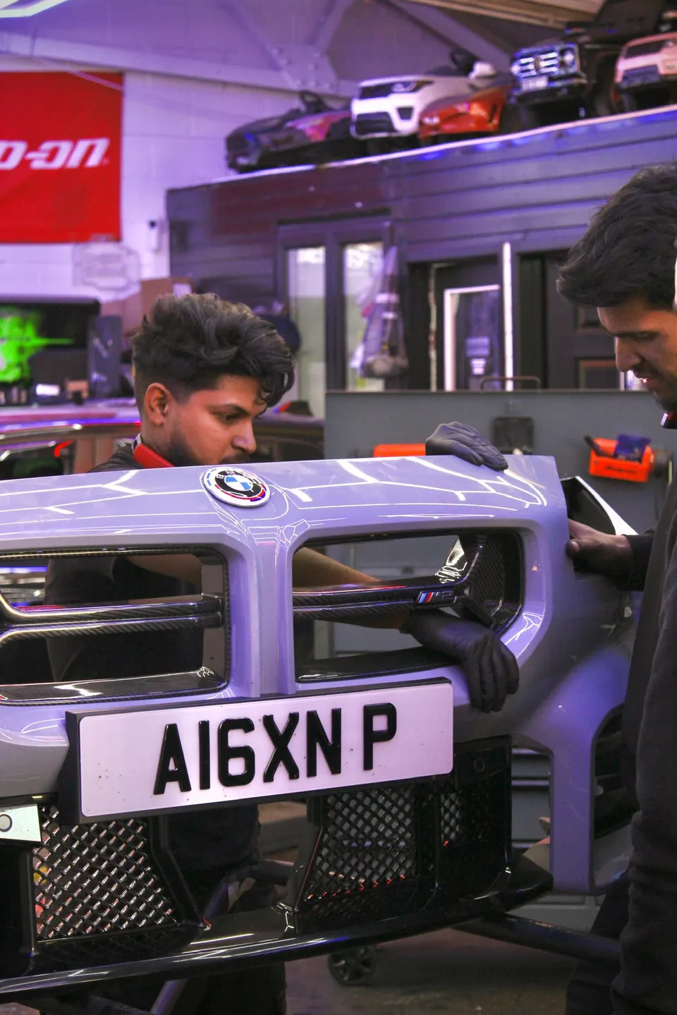 Technicians fitting the front grille of a BMW M2