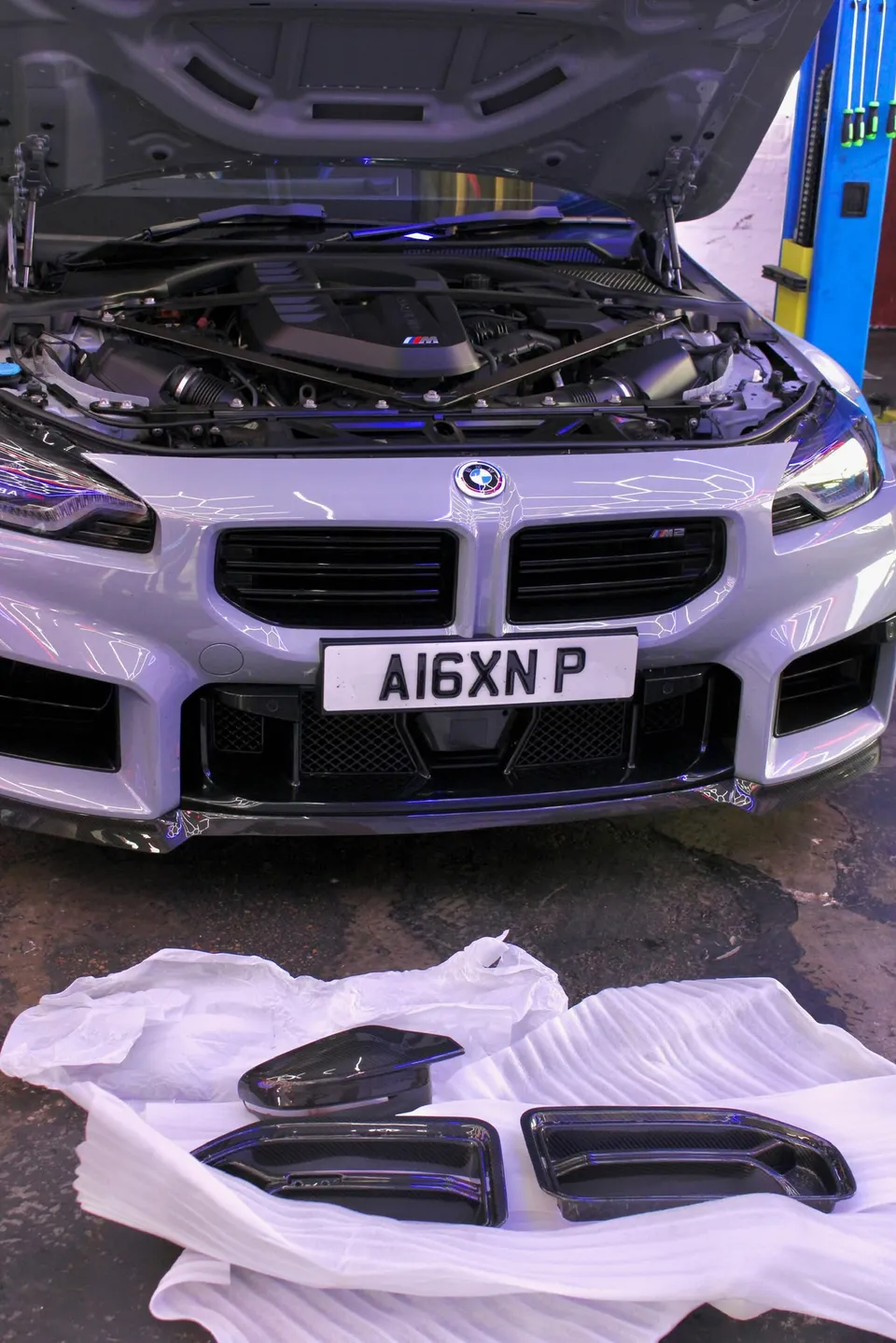BMW M2 with carbon parts laid out in front of it