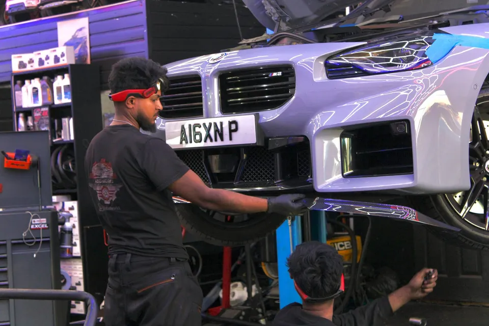 Two Abidworks technicians working on the front of a BMW M2