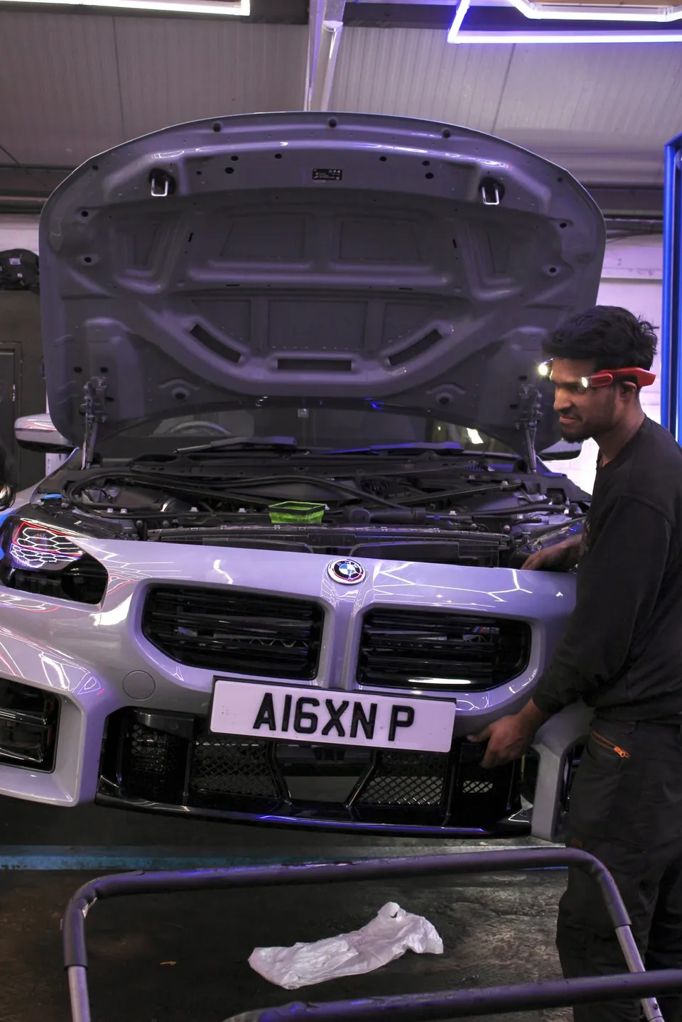Technician at the front of a BMW M2 with the bonnet up