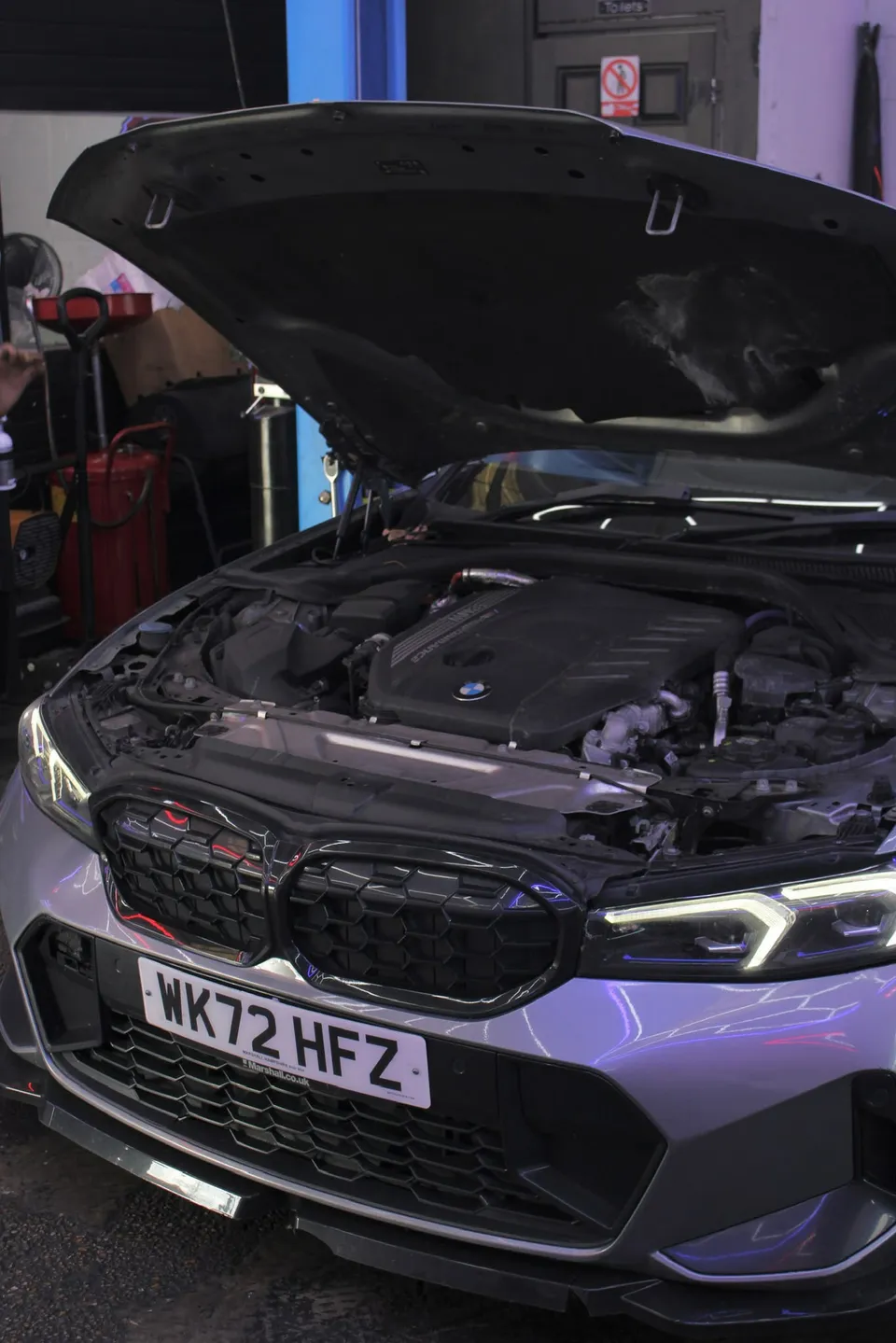 Grey BMW 3 Series with the bonnet up in the workshop