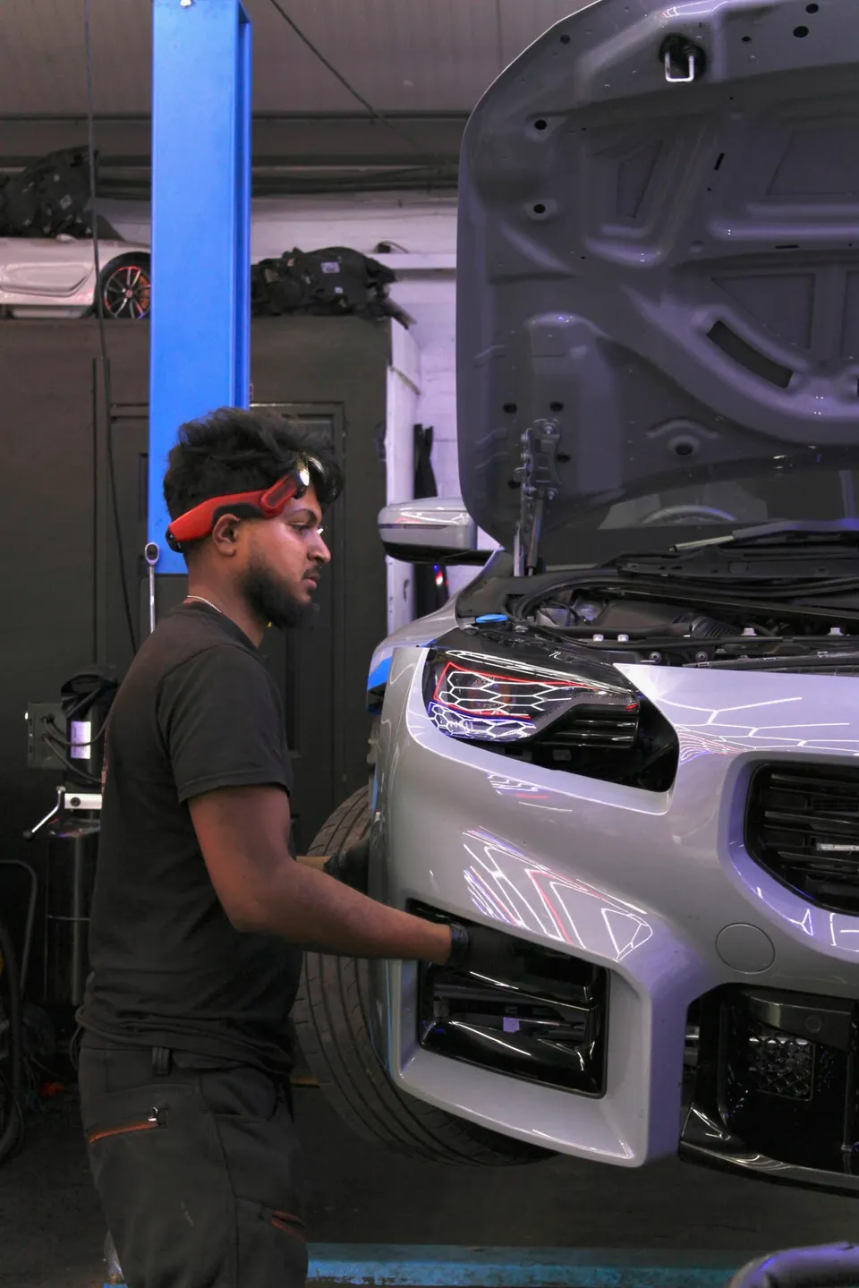 Technician at the front of a BMW M2 with the bonnet up