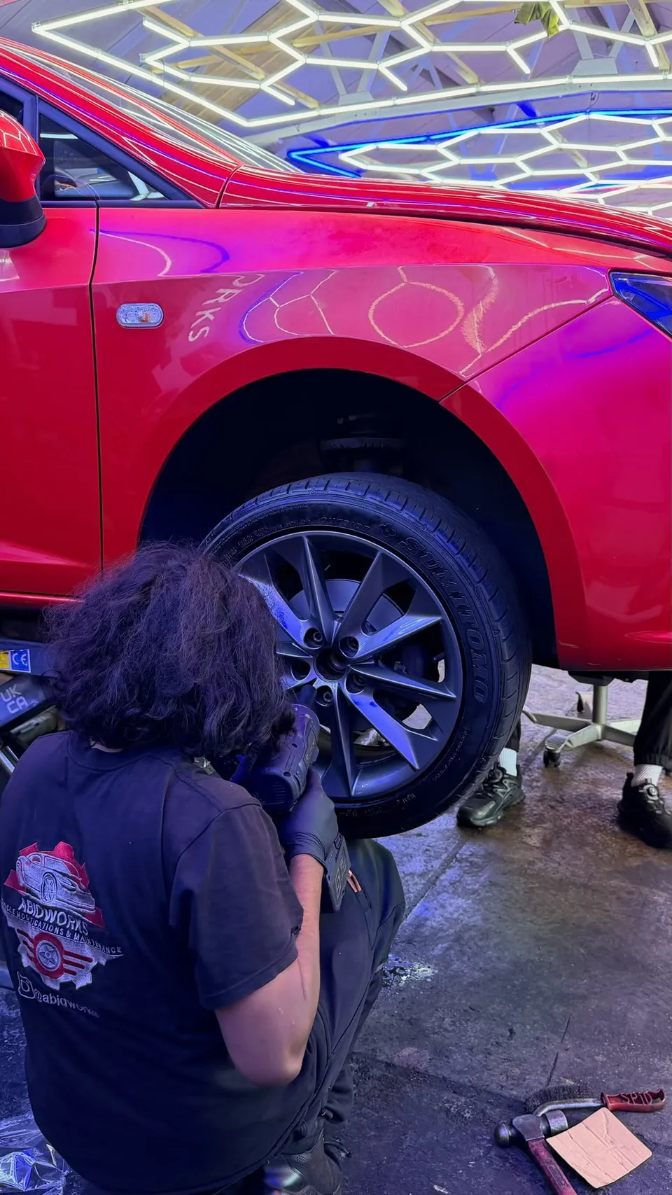 Technician at the front wheel of a red SEAT on the ramp