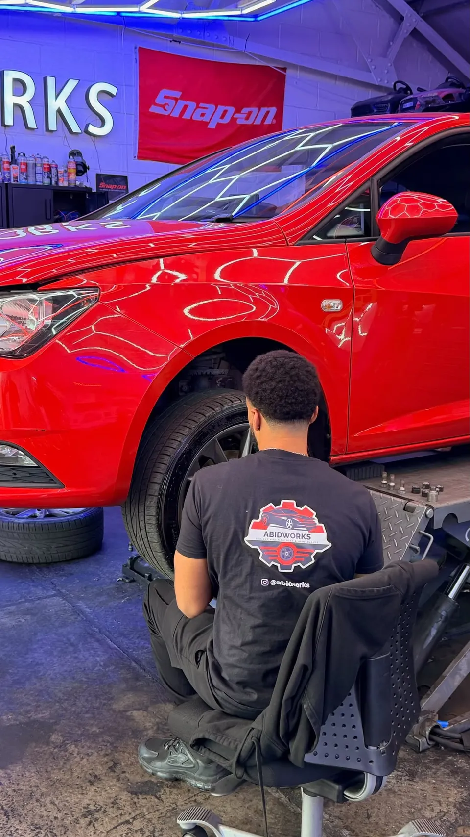 Technician working on the wheel of a red SEAT in the workshop