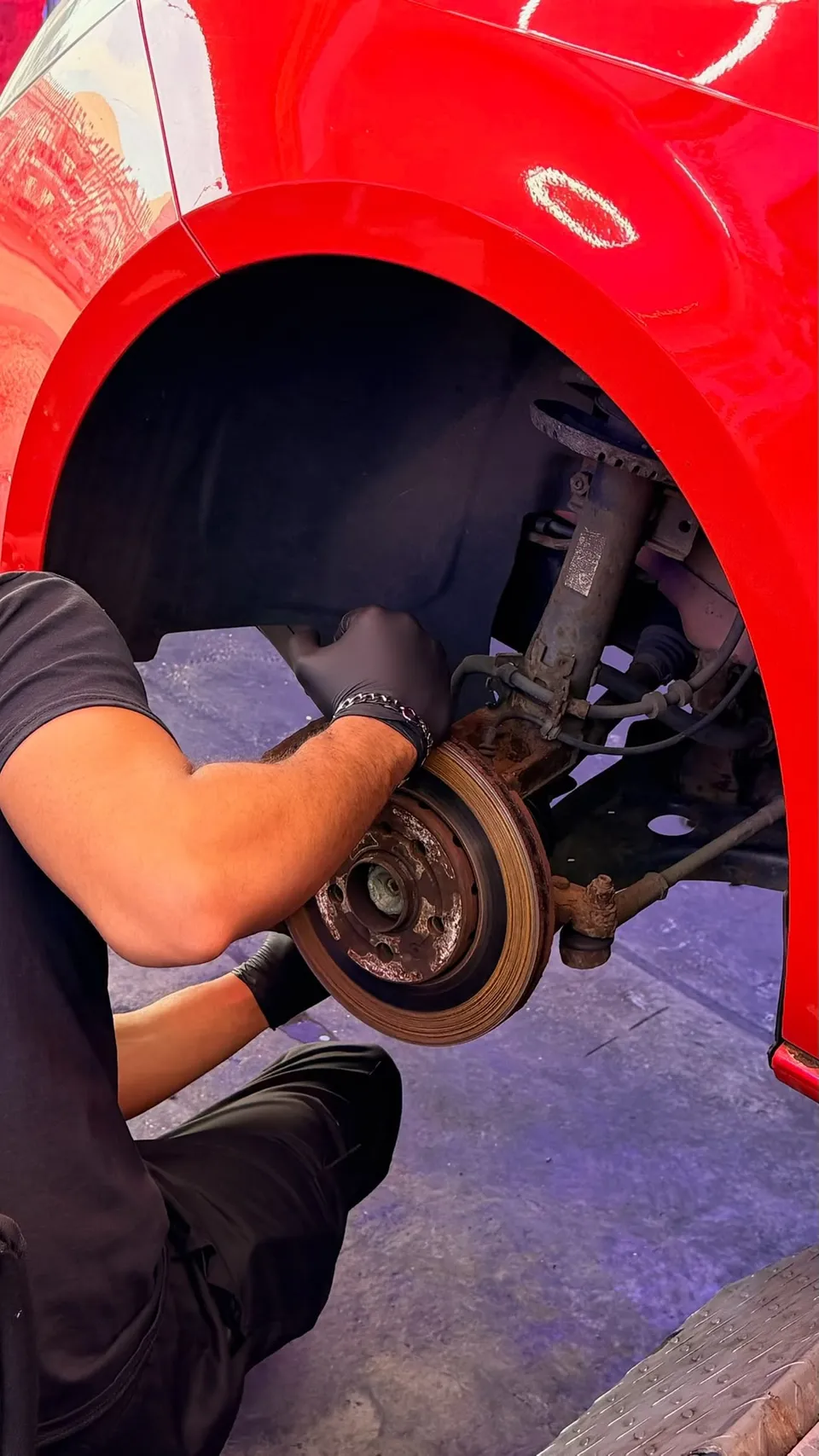 Technician working on a rear brake hub with the wheel off