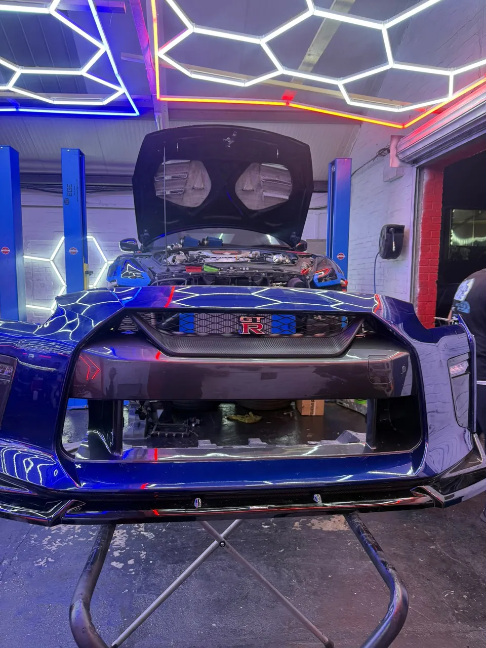Blue Nissan GT-R with the front bumper off in the Abidworks workshop