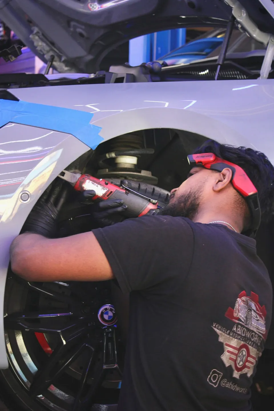Technician working at the front wheel arch of a BMW M2