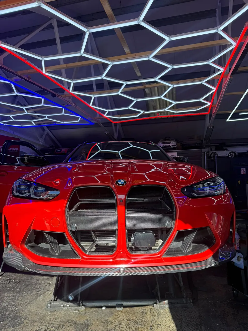 Front of a red BMW M3 on the ramp in the Abidworks workshop